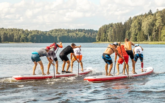 Deux équipes de quatre hommes effectuent une course sur des paddles géants