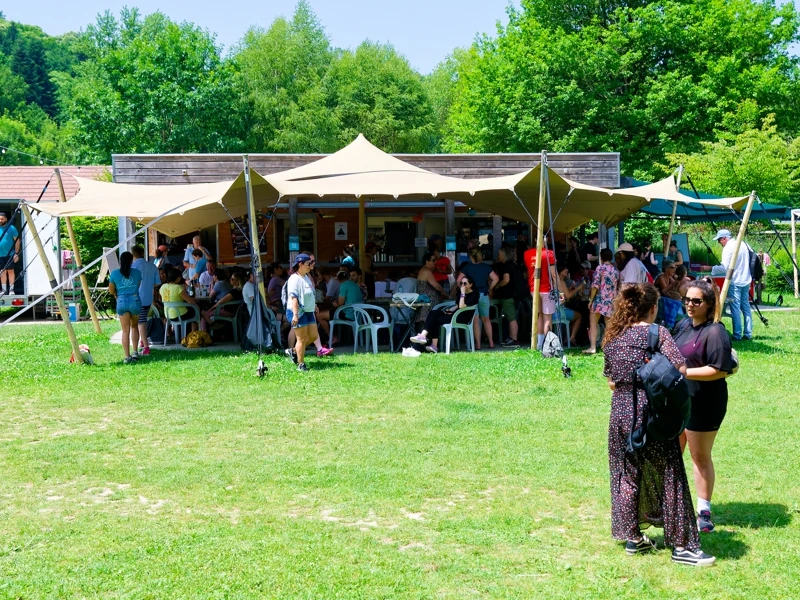 Des personnes sont réunies sur la terrasse d'un snack sous une grande tonnelle